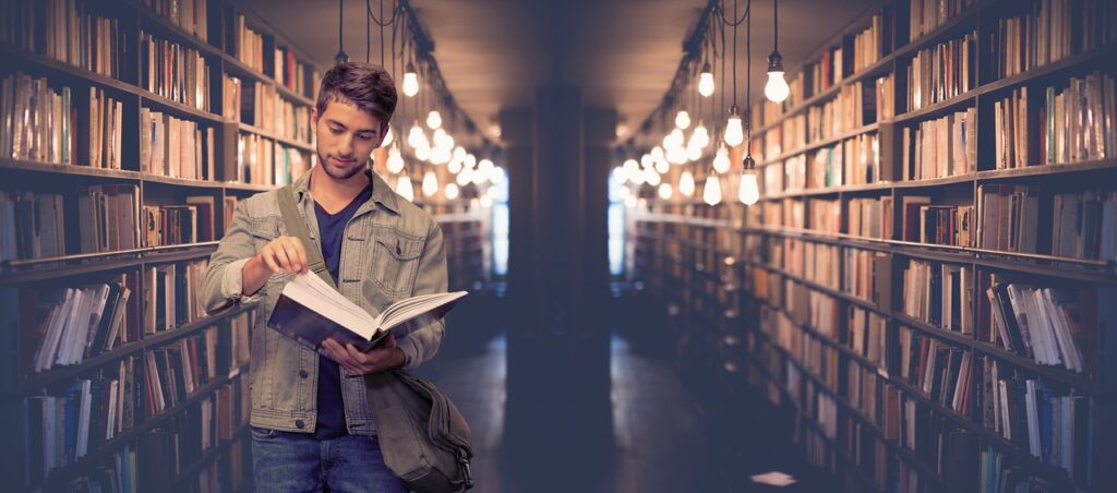 Male College student in the library looking for a book