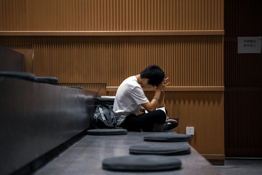 A sad male college student sitting down and thinking of what to do