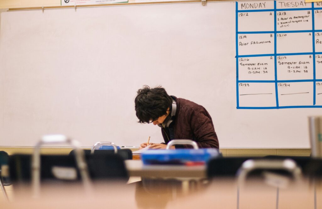 A male student writing on his book in class